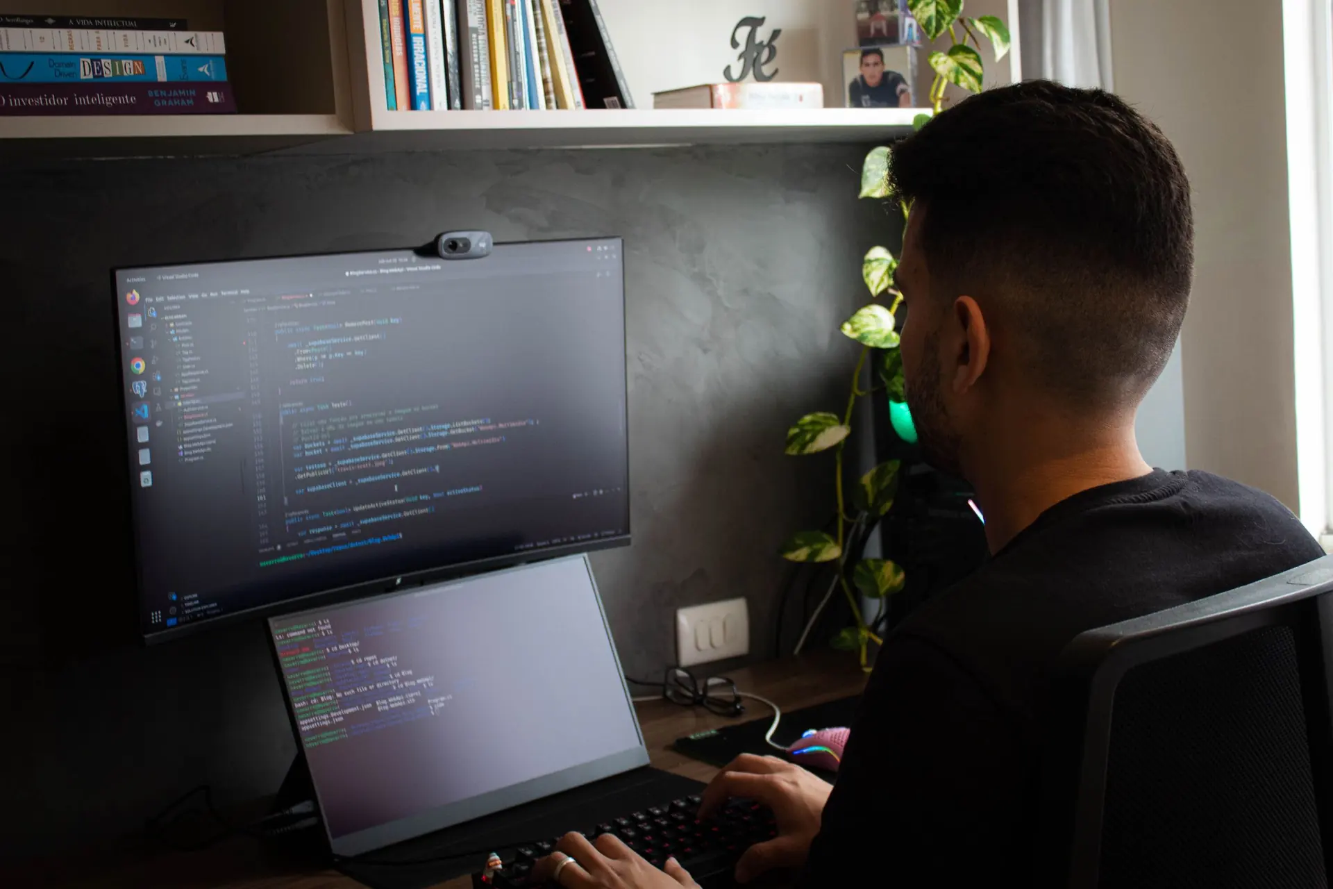 Developer coding at a desk with a monitor and laptop