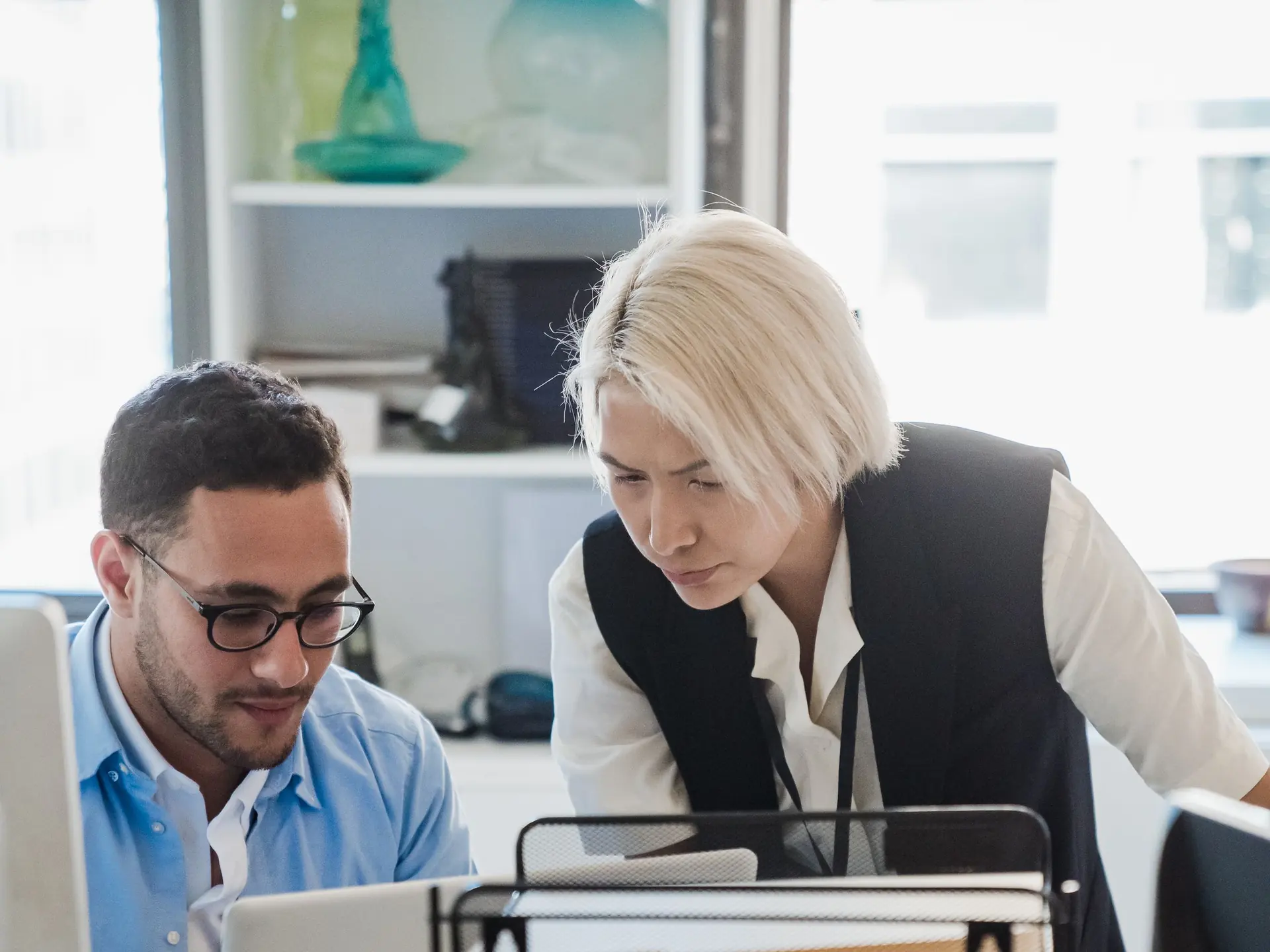 Two colleagues reviewing work together at an office desk