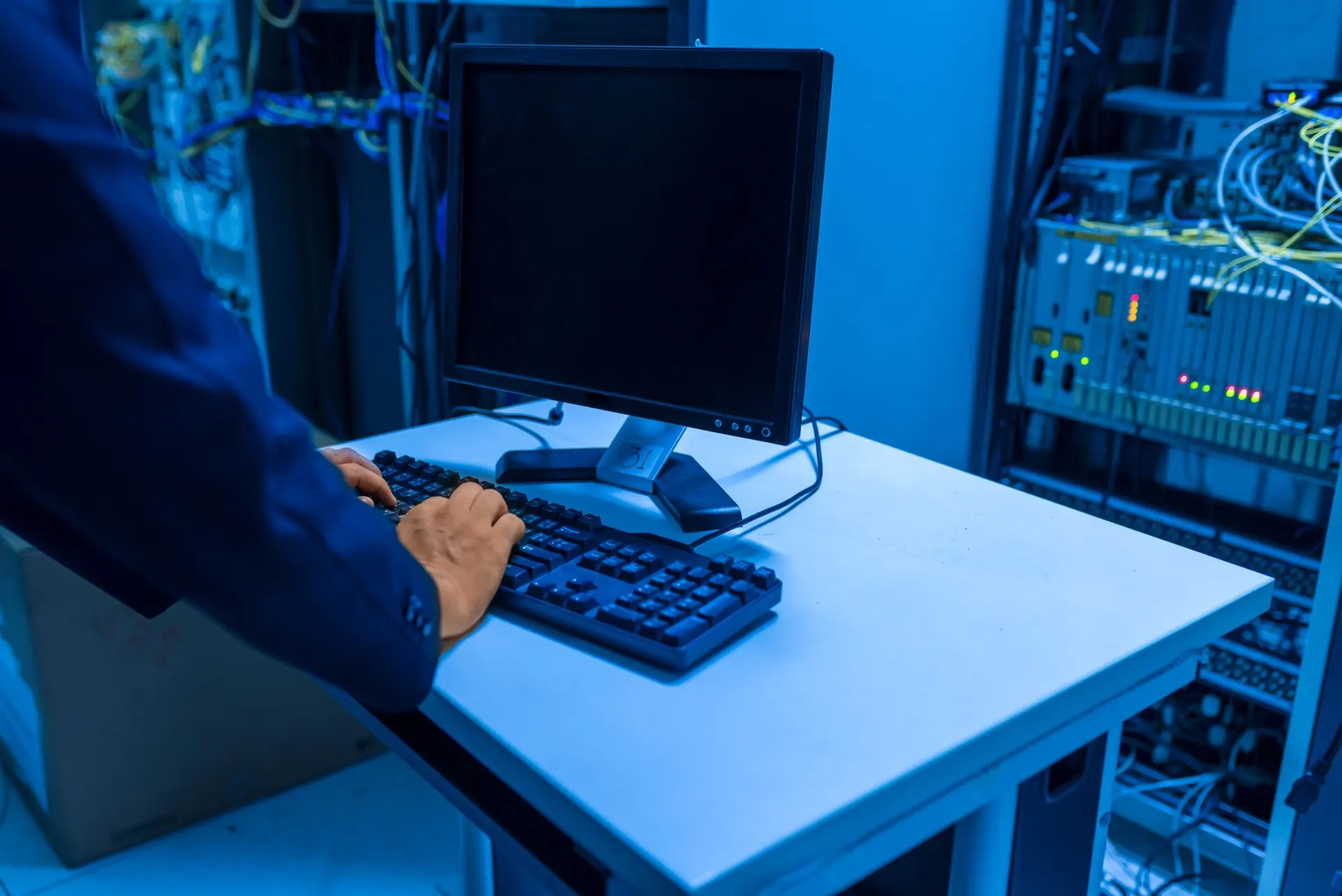 Technician working at a keyboard beside server equipment