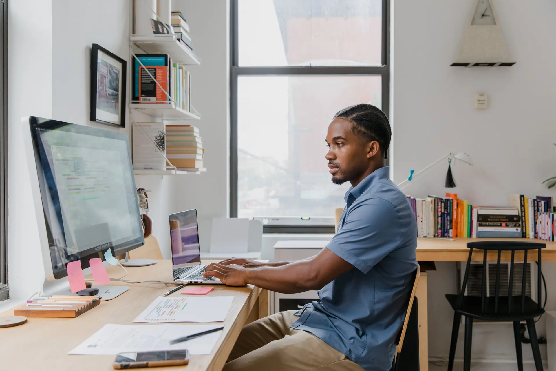 Engineer working at a desk with a monitor and laptop in a small office