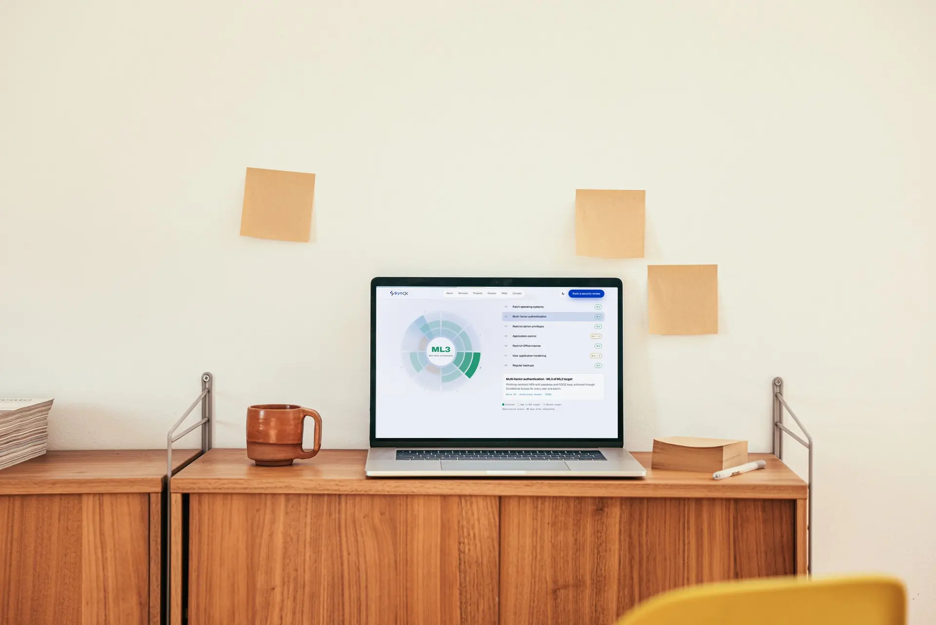 Laptop on a timber desk showing the SyncX Essential Eight posture view